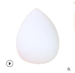 White teardrop makeup sponge puff on a plain background