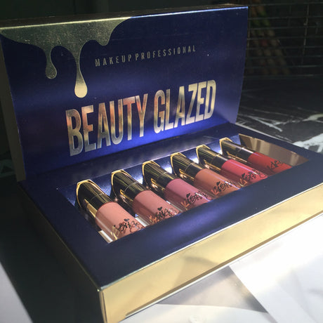 Open Beauty Glazed lipstick set with six shades on a dark marble surface