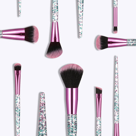 Scattered makeup brushes with pink ferrules, glitter handles and black-and-pink bristles