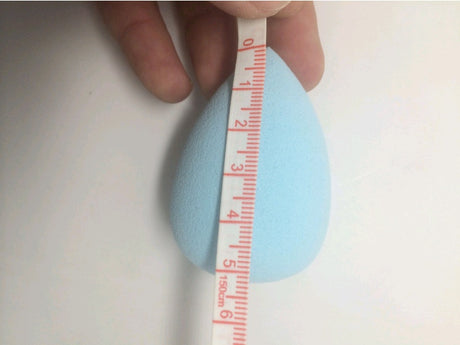 Blue Makeup Sponge Puff held beside a measuring tape showing centimetre marks