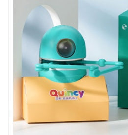 Turquoise drawing robot on a yellow Quincy box in a shelf setting