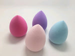 Four teardrop sponges in pink, pale pink, purple and blue on a white surface