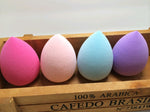 Four coloured teardrop sponges lined up in a wooden box