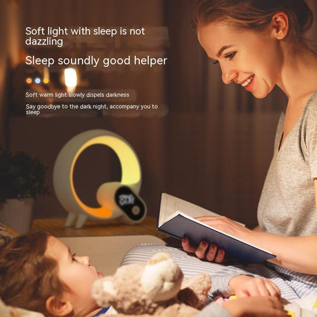Warm glowing Q Light clock on bedside table as an adult reads to a child