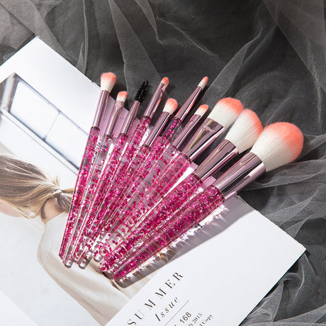 Pink glitter-handled makeup brushes with coral-tipped bristles on a magazine