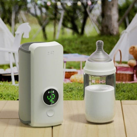 White warmer and a bottle on an outdoor garden table.