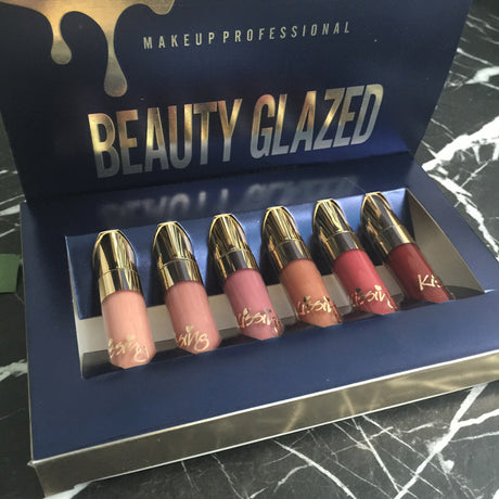 Open navy Beauty Glazed box showing six lipsticks from nude to red shades