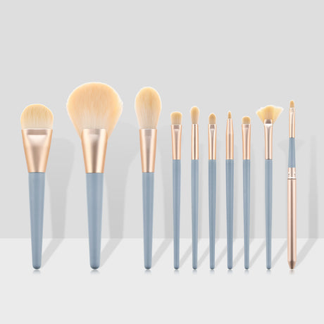 Ten makeup brushes standing upright with blue handles against a grey backdrop