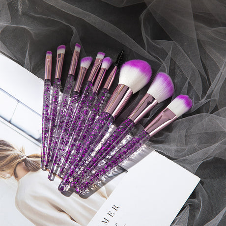 Fan of purple glitter makeup brushes on a magazine with grey mesh fabric