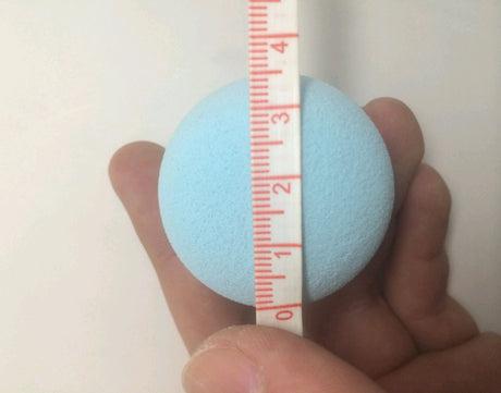 Blue round sponge held with a measuring tape showing centimetre marks