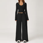 Women's black outfit with a long sleeve wrap top and wide leg trousers.
