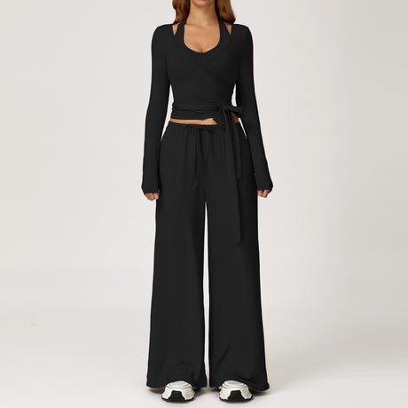 Women's black outfit with a long sleeve wrap top and wide leg trousers.