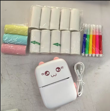 Pink mini printer with paper rolls, coloured pens and a white cable on a table