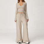 Women's beige long sleeve wrap top worn with matching wide leg trousers.