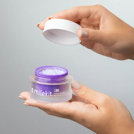 Hands opening a purple Smilekit powder jar with white powder visible