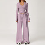 Women's lilac long sleeve wrap top worn with matching wide leg trousers.