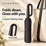 Compact folded NAMORRA umbrella with ring handle beside an everyday bag
